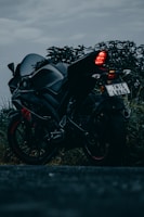 A rugged motorcycle parked on asphalt with a moody dark tone backdrop.