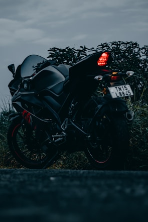 A rugged motorcycle parked on asphalt with a moody dark tone backdrop.