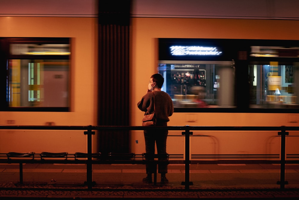 um homem de pé em uma plataforma de trem enquanto fala em um telefone celular