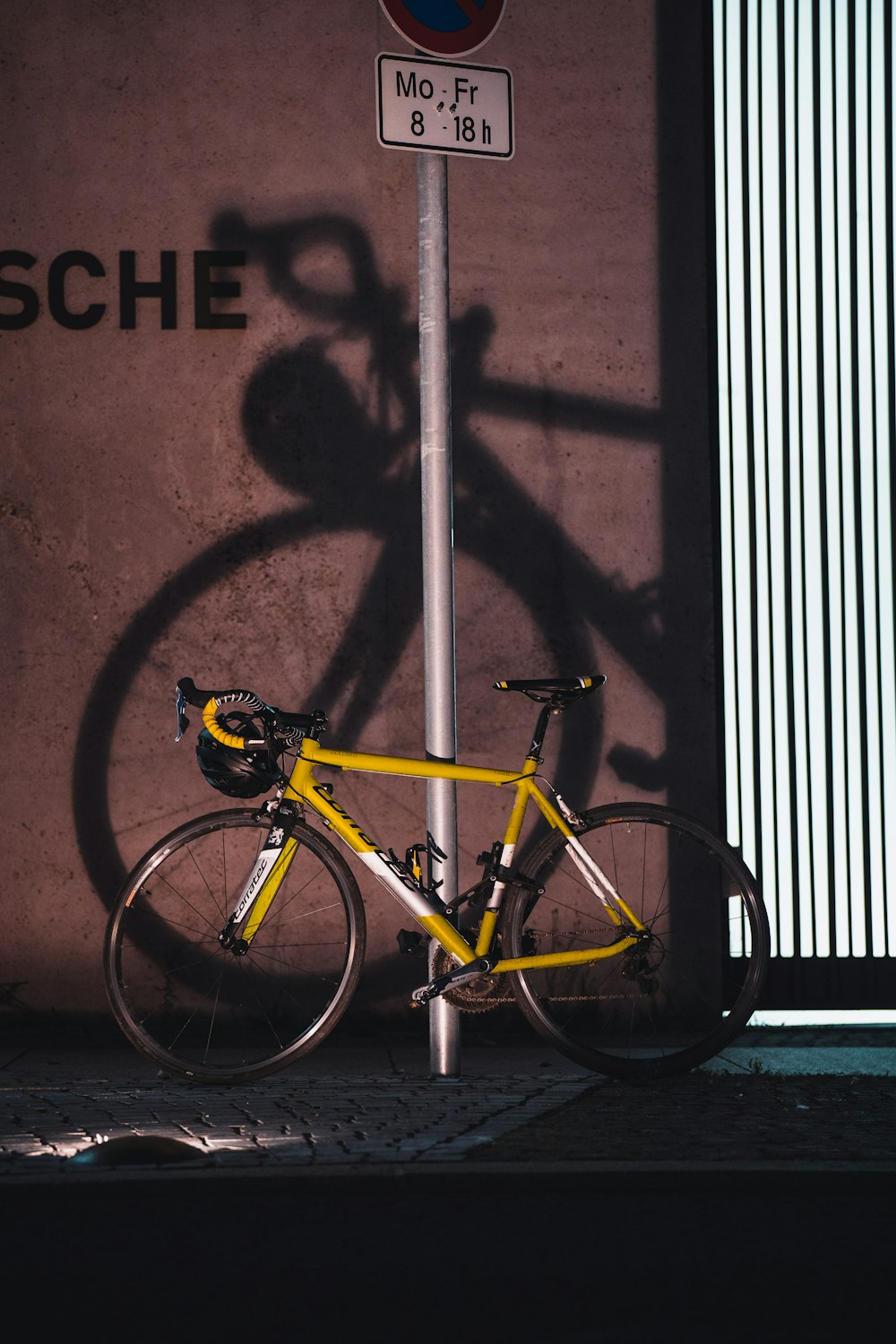 a yellow bike is parked next to a pole