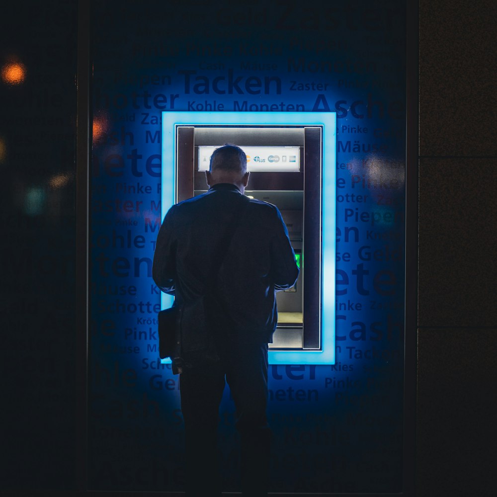um homem em pé na frente de uma máquina de caixa eletrônico