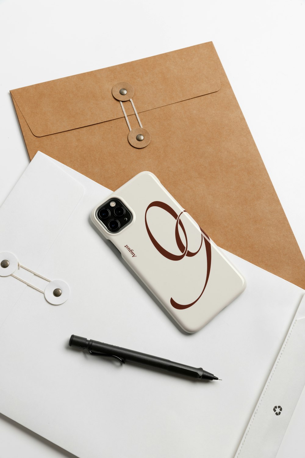 a cell phone sitting on top of a desk next to a pen