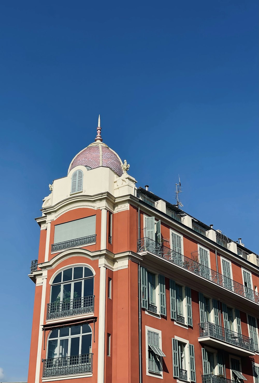 a tall red building with balconies on the top of it