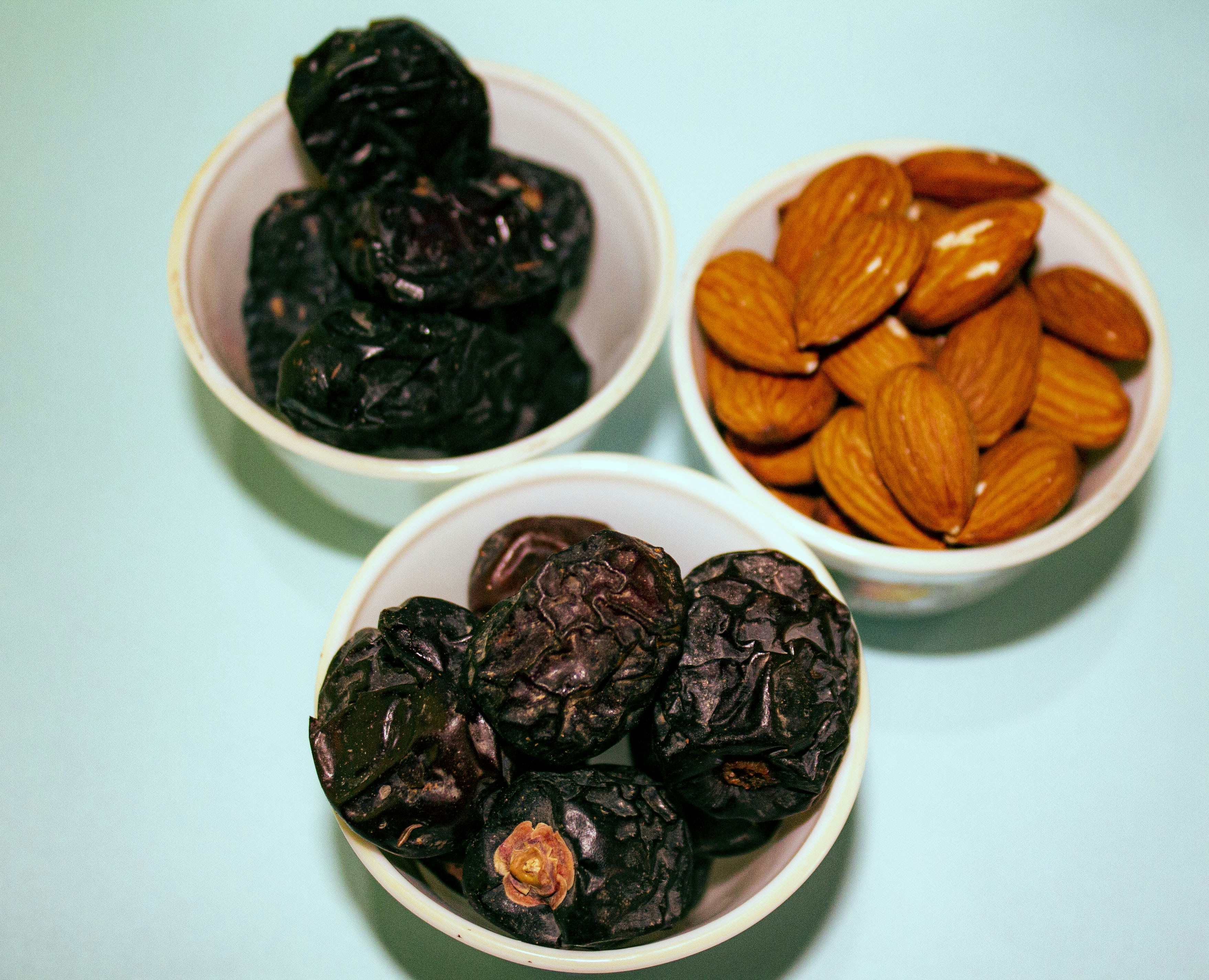 tiga mangkuk berisi kacang dan kismis di atas meja