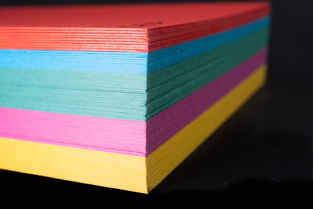a stack of multicolored paper on a black background