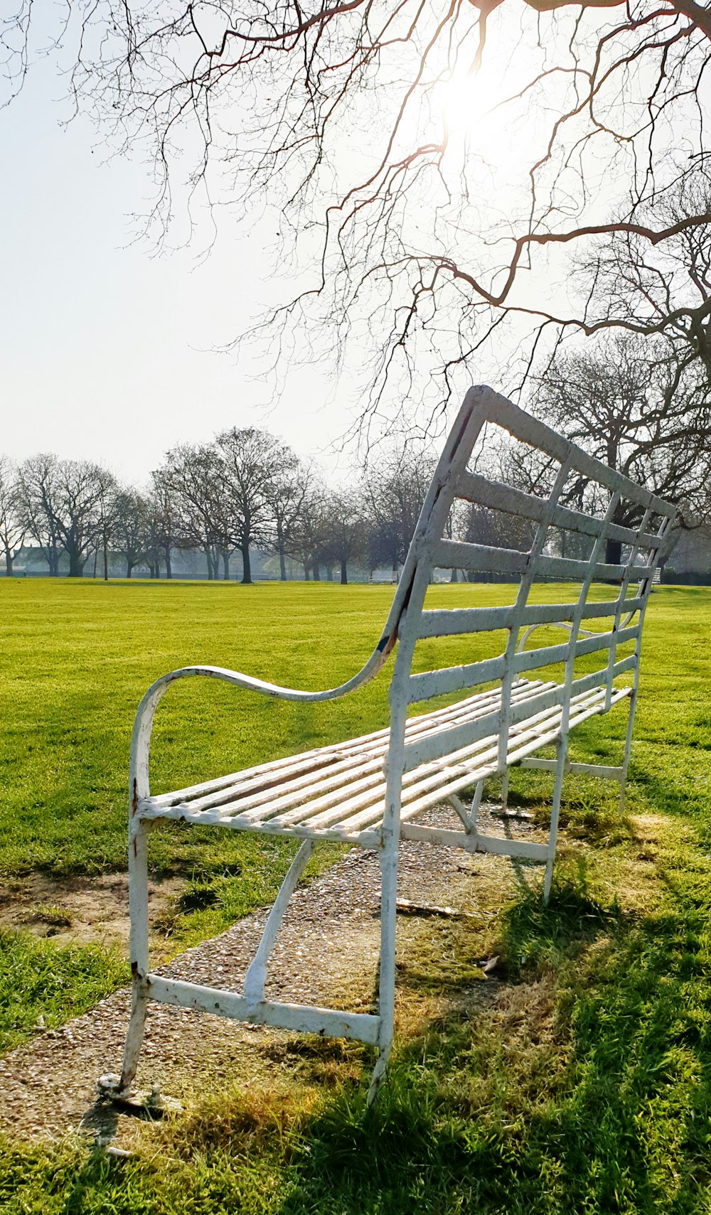 a white park bench sitting on top of a lush green field