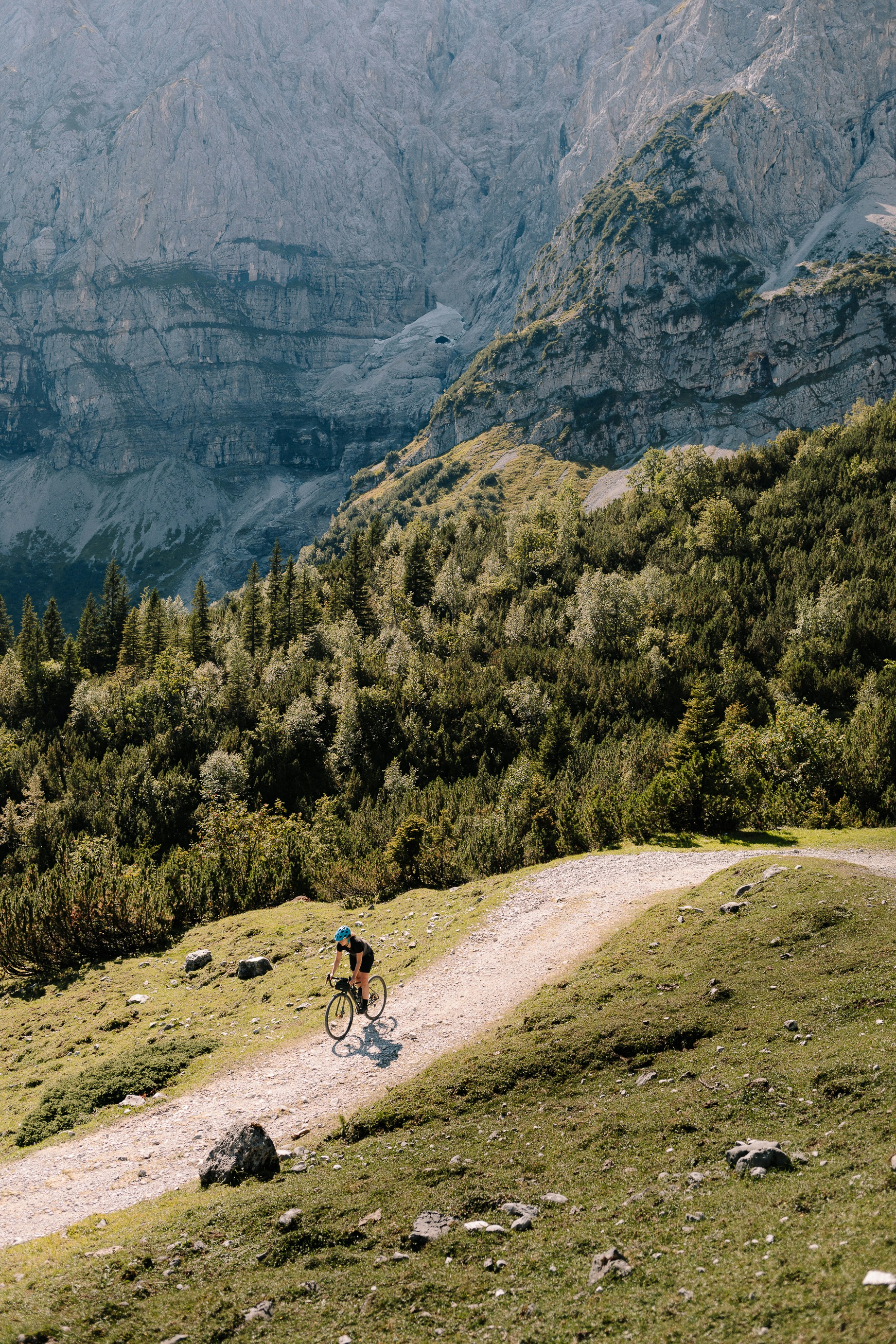 Karwendelgebirge, Austria: A young female cyclist on her gravel bike making her way up a gravel path into the mountains on a sunny morning.