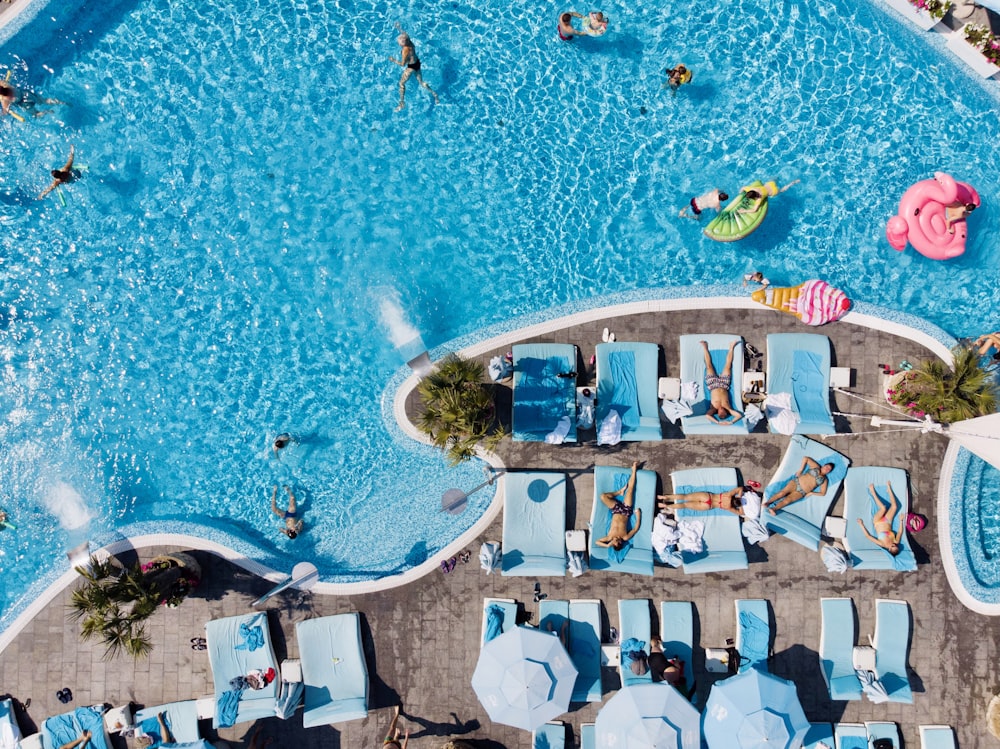 una vista cenital de una piscina con sillones y juguetes inflables