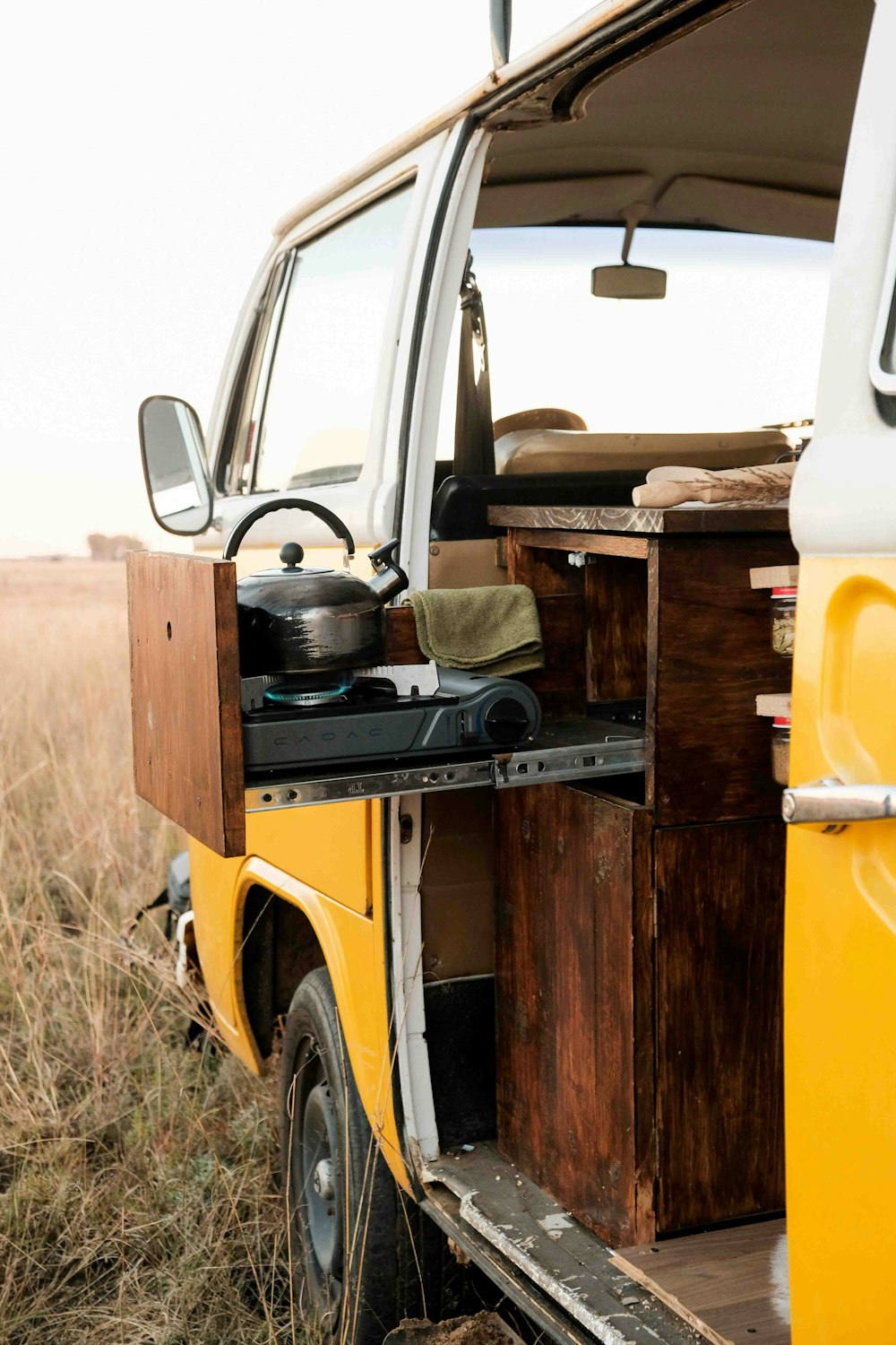 a yellow van parked in a field with its door open