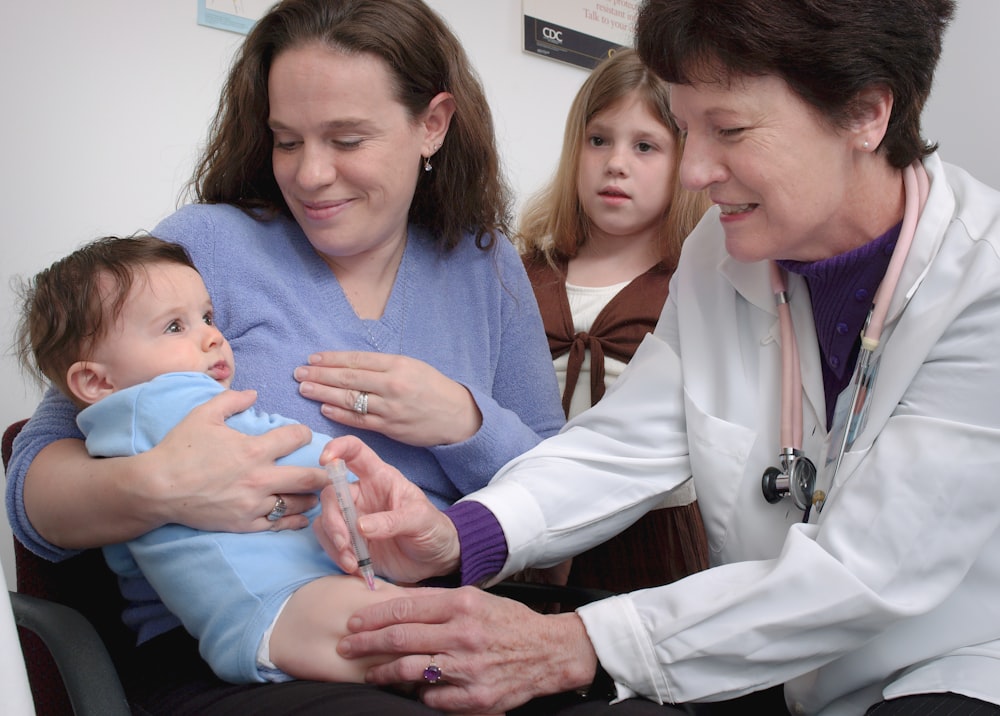 a woman in a white coat is holding a baby