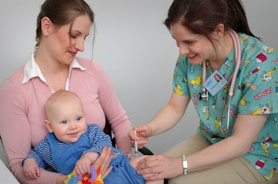 A smiling nurse providing medical care to a child in a bright, cheerful environment.