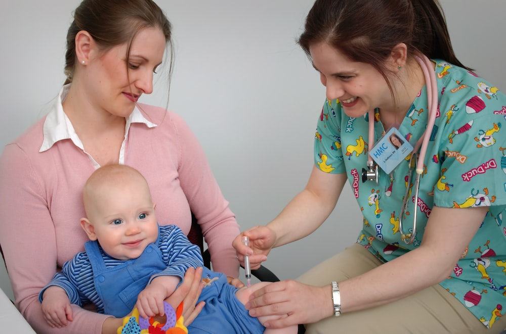 a woman in scrubs is holding a baby