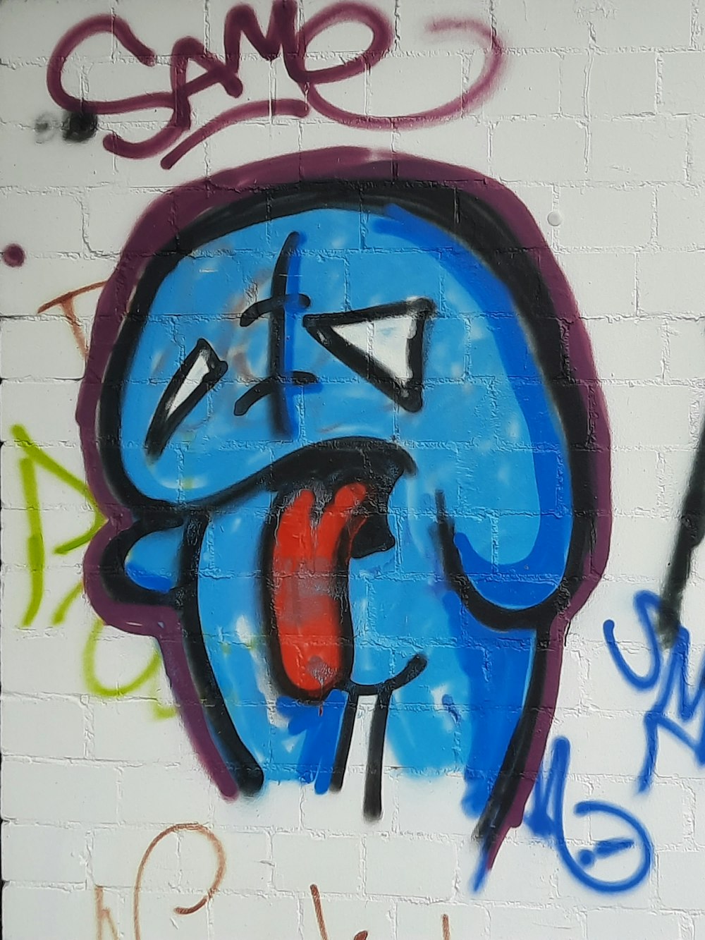graffiti on a white brick wall with a blue face