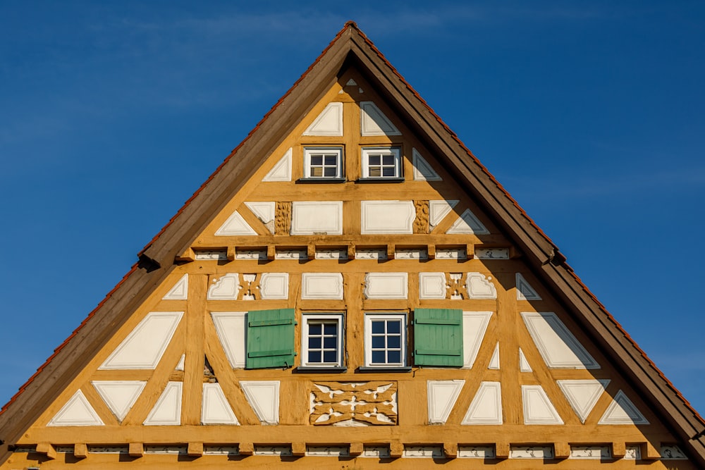 a tall wooden building with green shutters and a clock