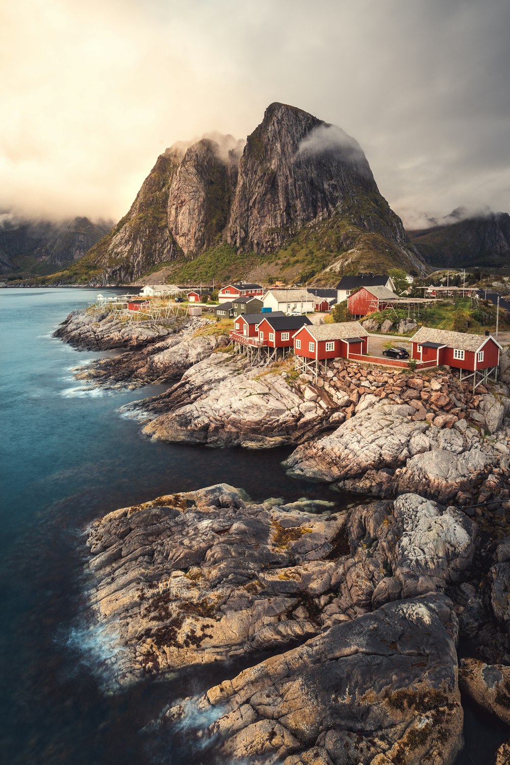a scenic view of a rocky coastline with houses and mountains in the background