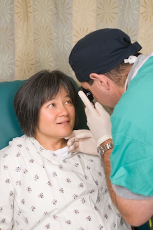 a woman in a hospital gown getting her teeth checked