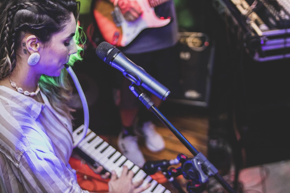 a woman sitting in front of a microphone while playing a keyboard