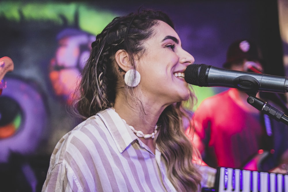 a woman singing into a microphone while holding a keyboard