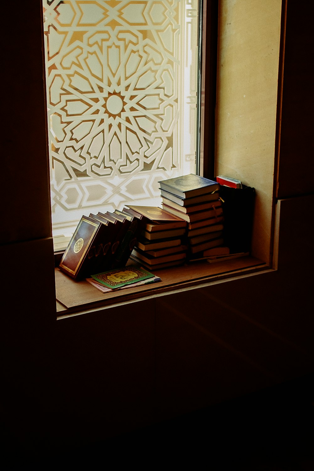 a stack of books sitting on top of a window sill