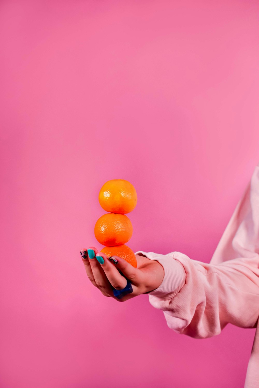 a woman holding three oranges in her hand