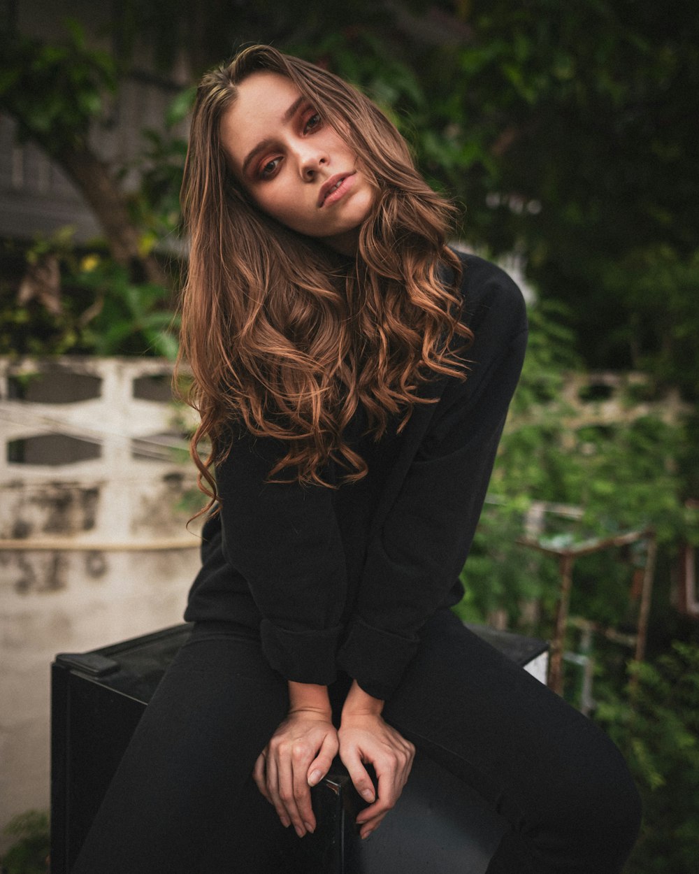 uma mulher com cabelo comprido sentado em uma mala