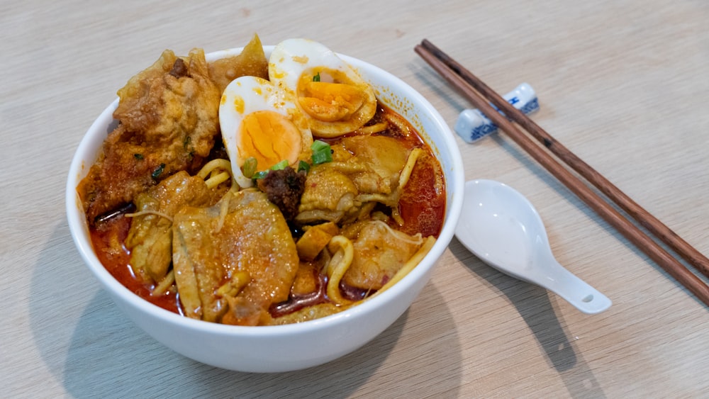 a bowl of food with chopsticks on a table