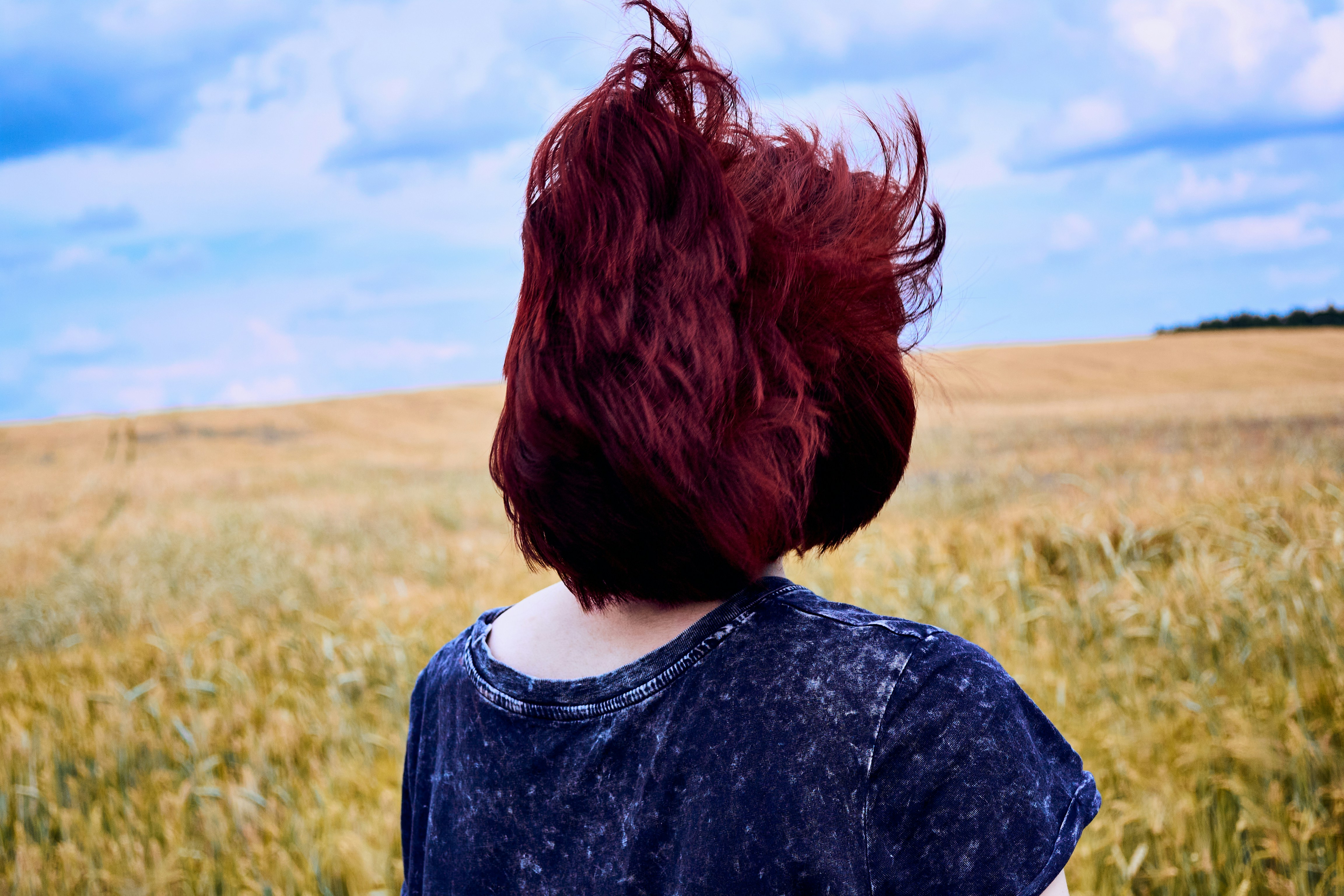 une femme aux cheveux roux debout dans un champ