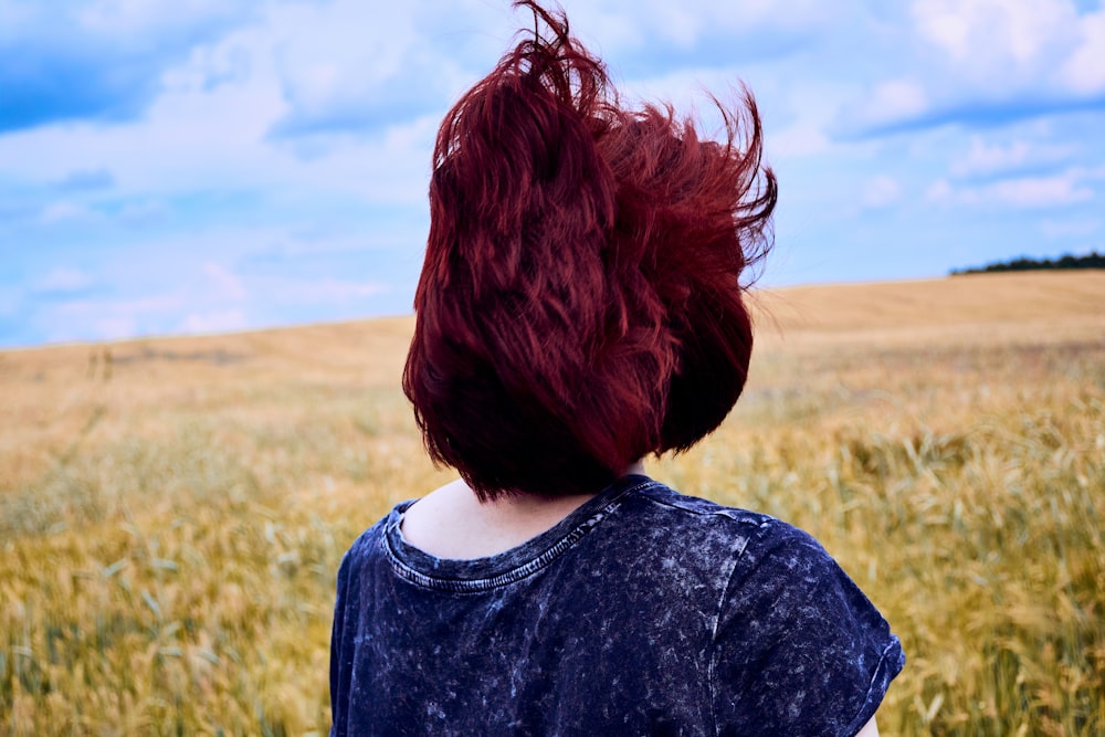 a woman with red hair standing in a field