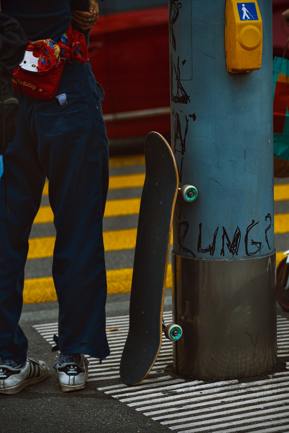 uma pessoa em pé ao lado de um poste com um skate