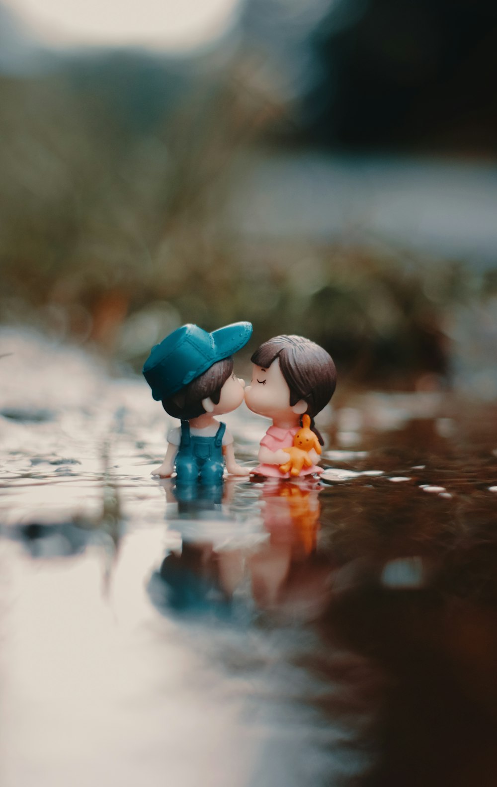 A couple of small figurines sitting on top of a body of water ...