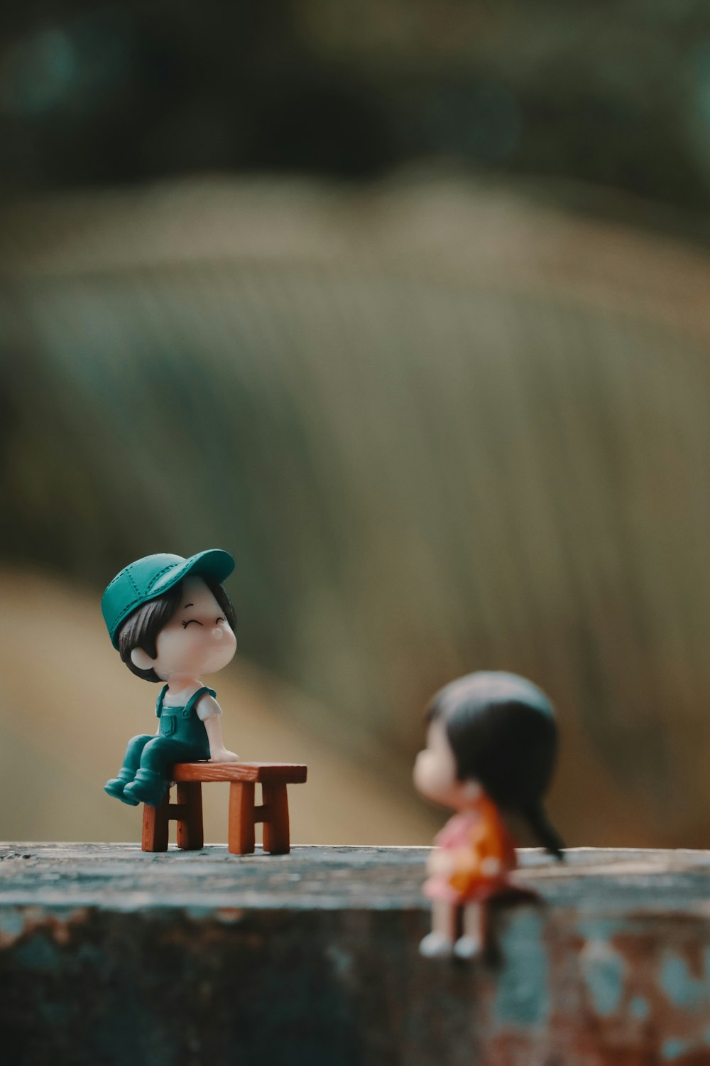 a couple of small figurines sitting on top of a wooden bench