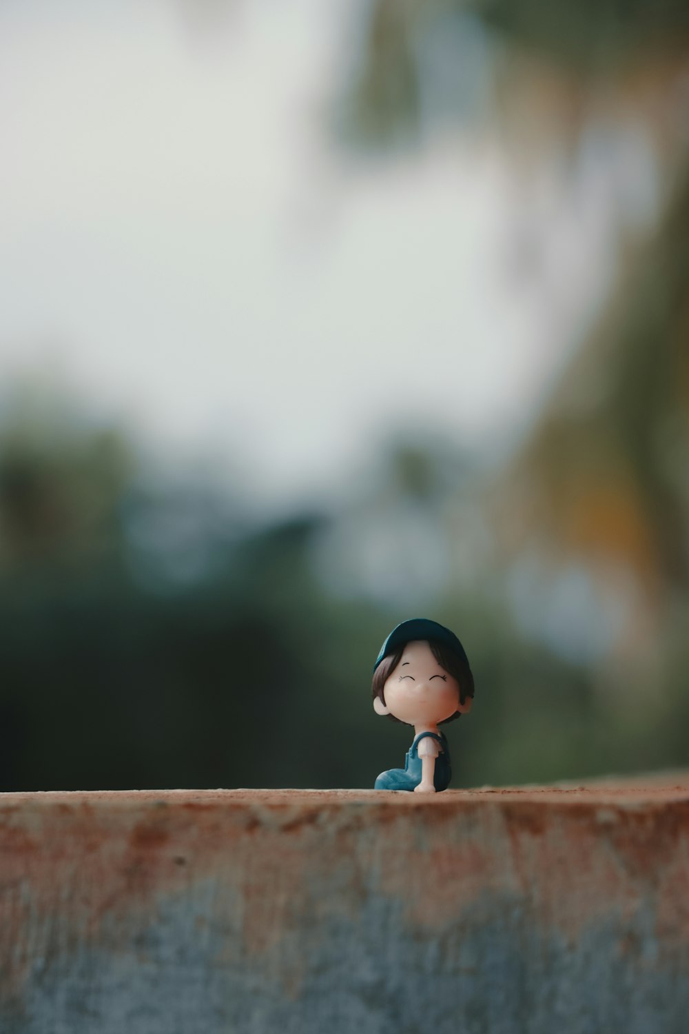a small figurine sitting on top of a cement wall