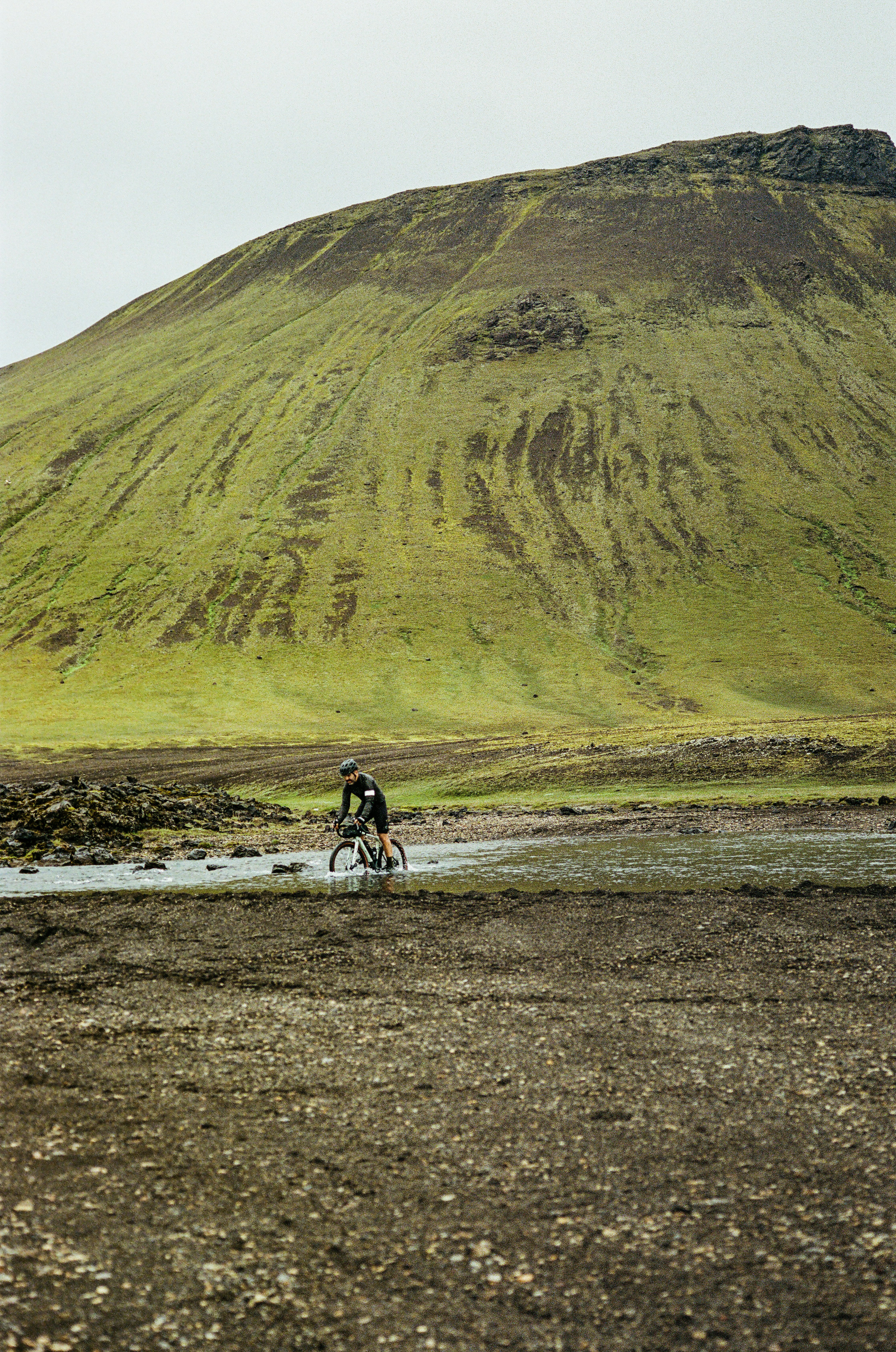 a man riding a bike down a muddy road