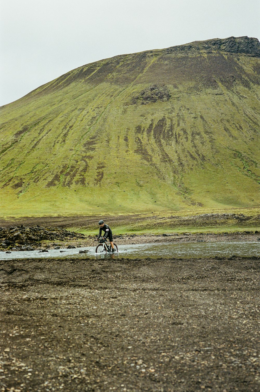 a man riding a bike down a muddy road
