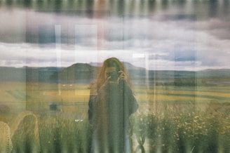a woman standing in front of a window in a field