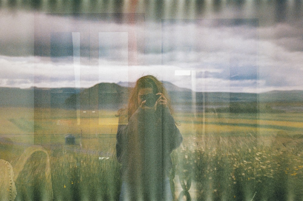 a woman standing in front of a window in a field