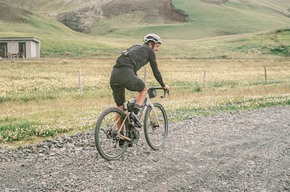 a man riding a bike down a gravel road