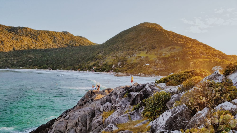 a group of people standing on top of a mountain next to the ocean