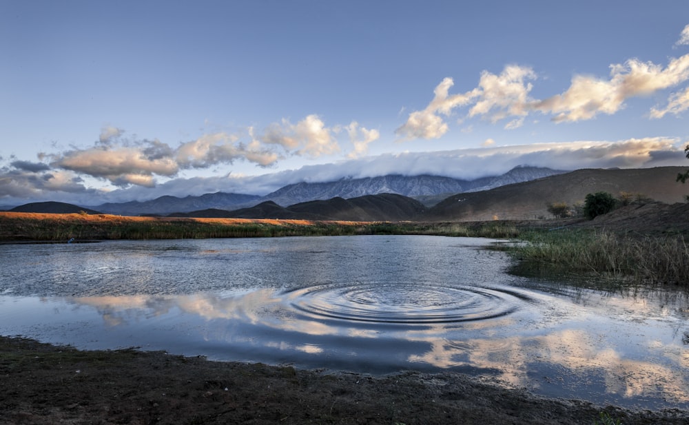 un plan d’eau entouré de montagnes sous un ciel nuageux