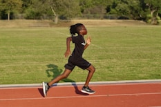 a young girl running on a track in a park