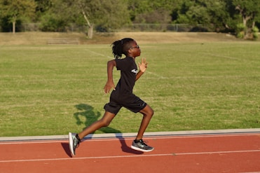 a young girl running on a track in a park