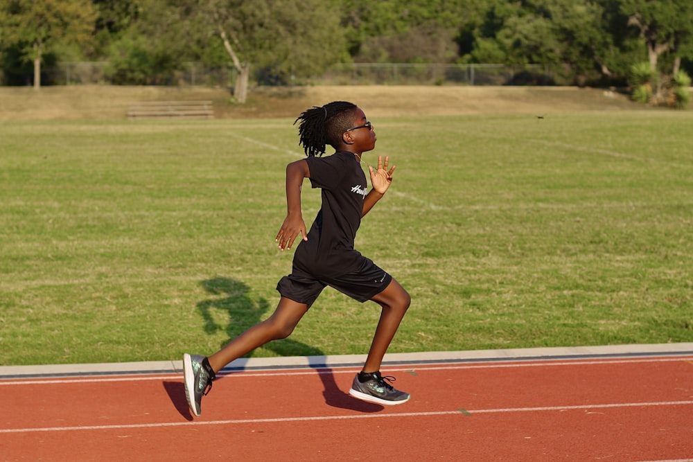 a young girl running on a track in a park