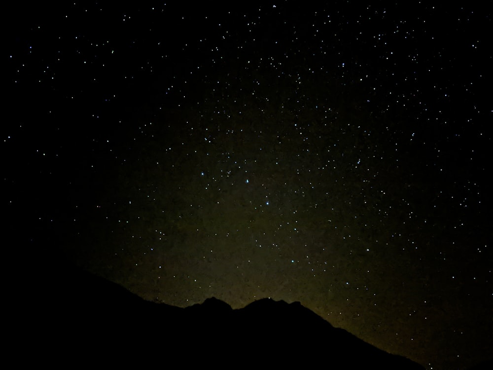 the night sky with stars above a mountain range