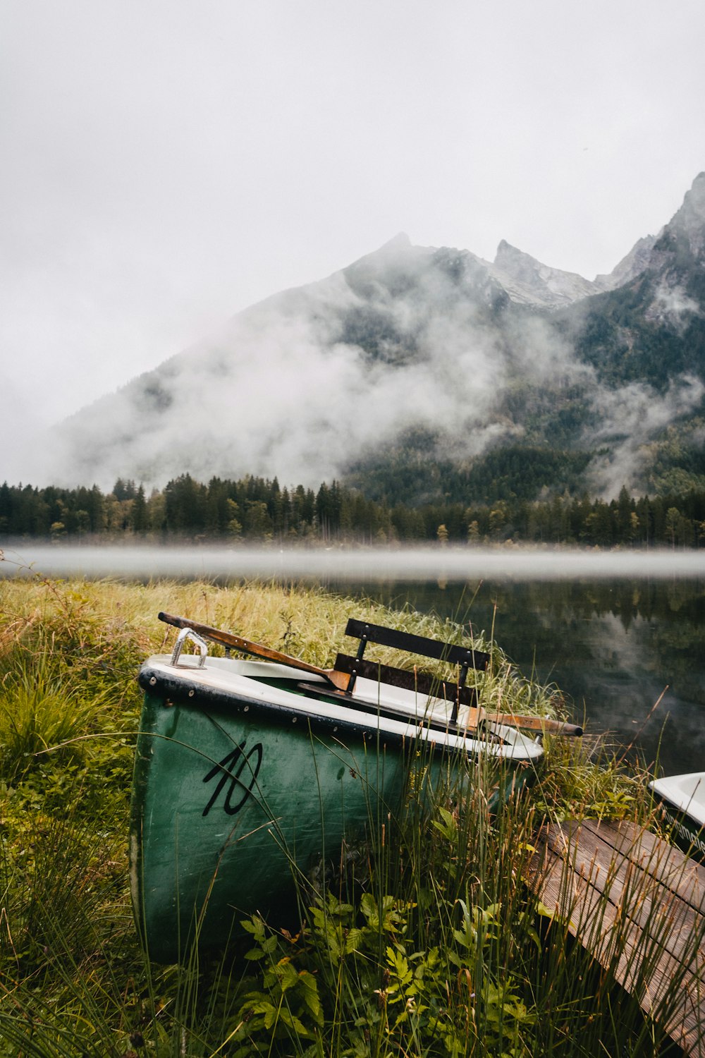 a green boat sitting on top of a grass covered field