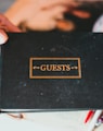a person holding a black book with the word guests on it