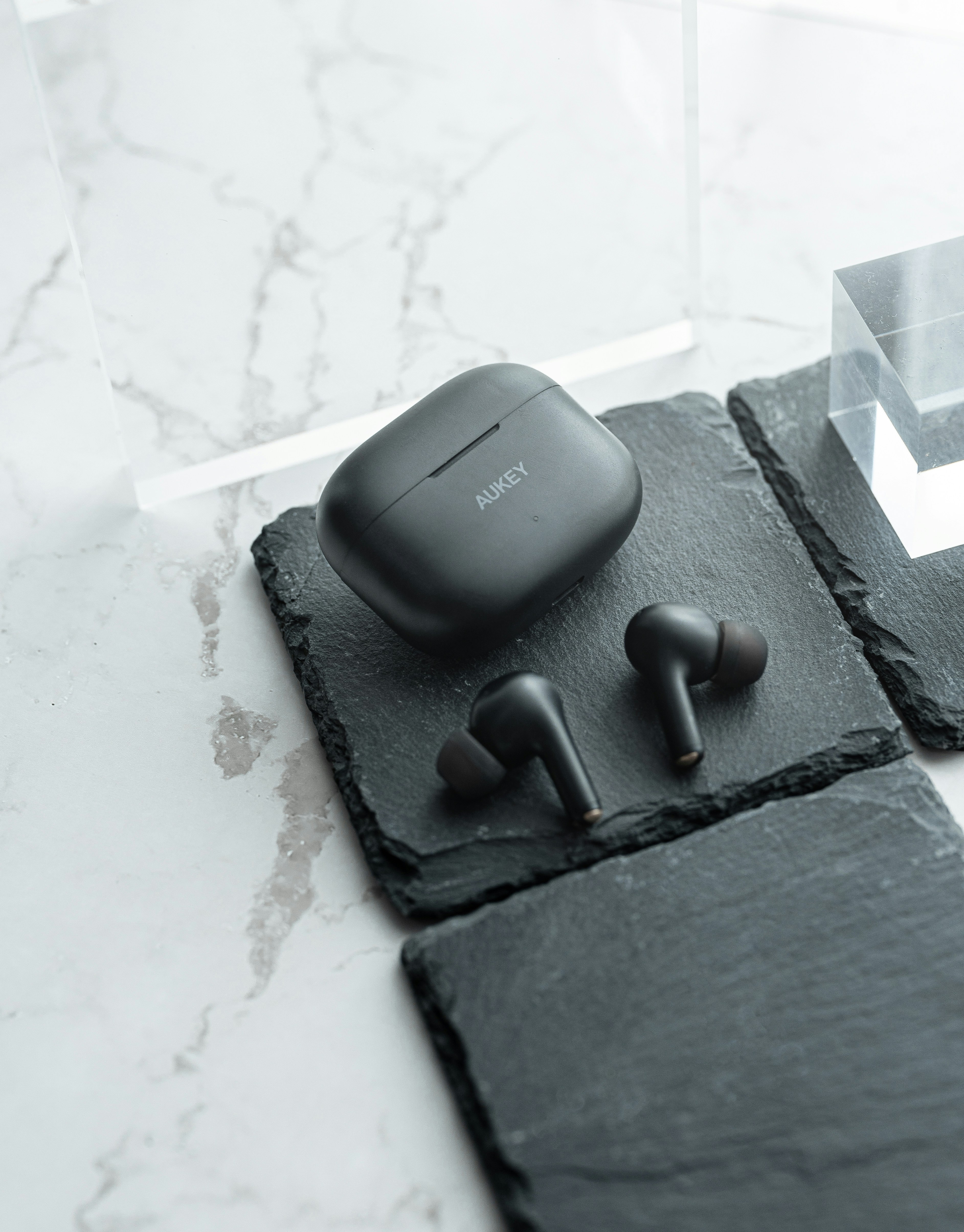 a pair of ear buds sitting on top of a black piece of slate
