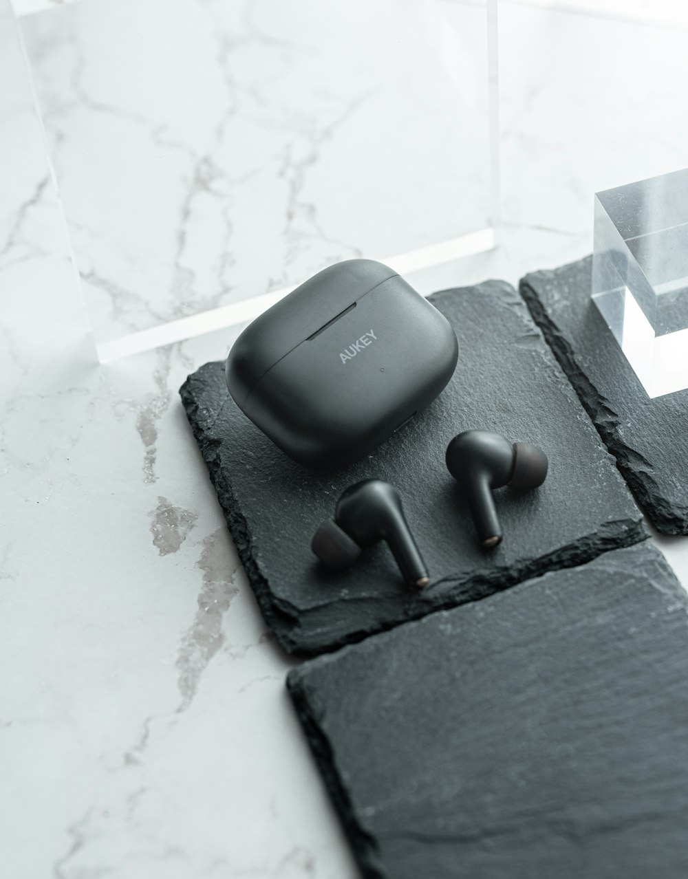 a pair of ear buds sitting on top of a black piece of slate