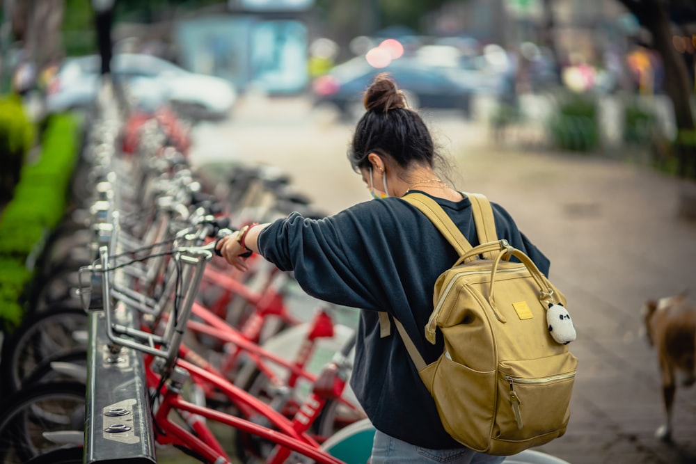 a woman with a back pack walking a line of bikes