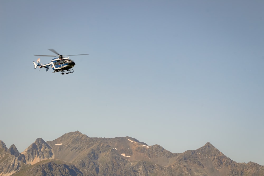 a helicopter flying over a mountain range on a clear day