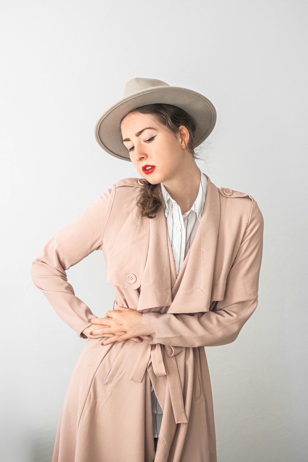 uma mulher em um trench coat e chapéu posando para uma foto